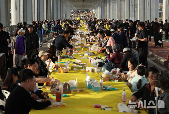 [서울=뉴시스] 김명년 기자 = 25일 서울 잠수교에서 열린 차 없는 잠수교 뚜벅뚜벅 축제의 마지막 행사인 ‘잠수교 치킨데이’에서 시민들이 다양한 브랜드의 치킨을 맛보고 있다. 잠수교는 26일부터 차량 통행이 전면 통제되며 한강 보행전용교 조성을 위한 공사에 들어간다. 2026.10.25. kmn@newsis.com