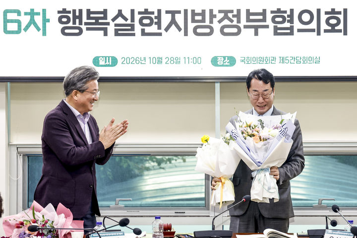 [화성=뉴시스] 정명근 화성시장(사진 오른쪽)이 '행복실현지방정부 협의회 2026년 정기총회'에서 제5기 공동회장으로 선출되면서 받은 꽃다발을 바라보고 있다. (사진=화성시 제공) 2026.10.28. photo@newsis.com *재판매 및 DB 금지