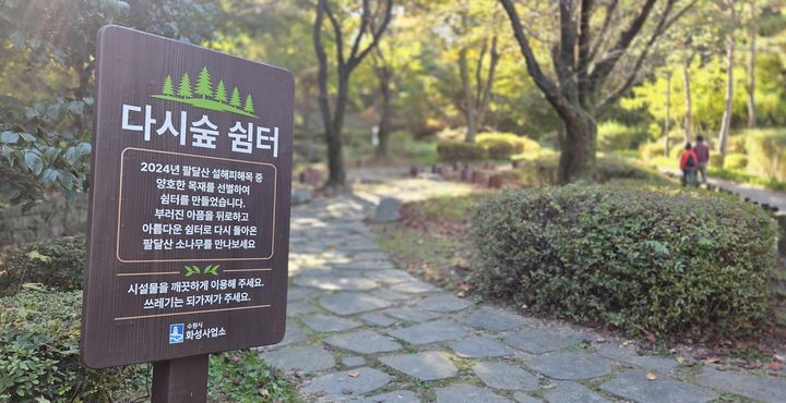 [수원=뉴시스] 수원시가 팔달산에 조성한 '다시숲쉼터' 입구에 안내판이 설치돼 있다. 시는 2024년 폭설로 쓰러진 소나무를 의자로 만들어 쉼터에 놓았다. (사진=수원시 제공) 2026.10.29. photo@newsis.com *재판매 및 DB 금지