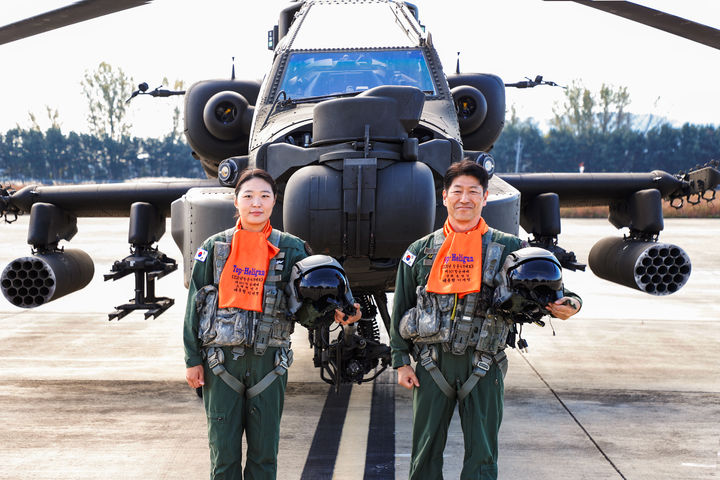 [서울=뉴시스] 2026 육군항공 사격대회 '탑 헬리건(Top Heligun)'으로 선발된 편연주 소령(좌), 송영일 준위(우)가 아파치(AH-64E) 헬기 앞에서 포즈를 취하고 있다. (사진=육군 제공) 2026.10.30. photo@newsis.com *재판매 및 DB 금지