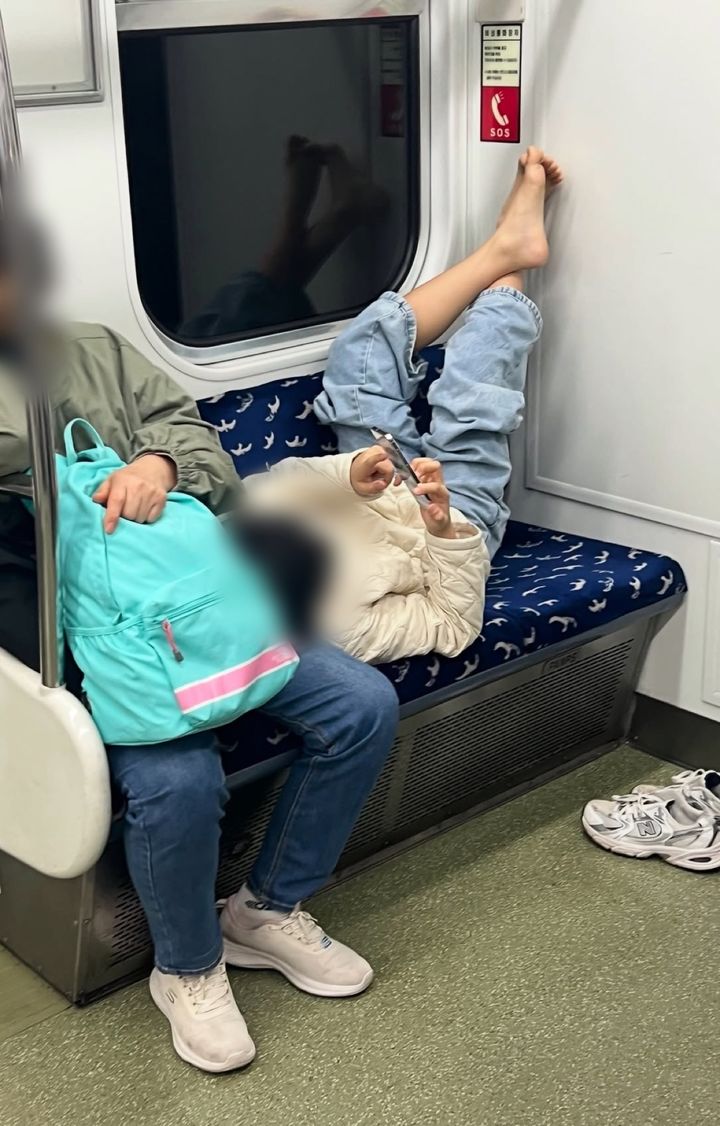 [서울=뉴시스] 지하철 노약자석에서 신발을 벗고 맨발로 누워 휴대전화를 사용하는 아이의 모습이 공개돼 공공장소 예절을 둘러싼 지적이 나왔다. (사진출처=스레드 캡처) *재판매 및 DB 금지